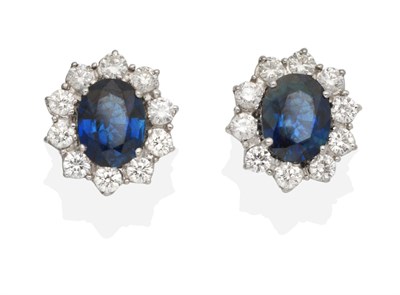 Lot 353 - A Pair of Sapphire and Diamond Cluster Earrings, an oval cut sapphire within a border of round...