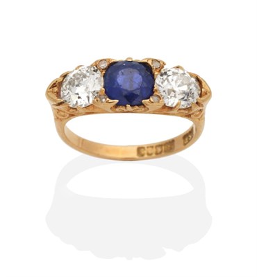 Lot 414 - An 18 Carat Gold Three Stone Sapphire and Diamond Ring, a round cut sapphire between two old...