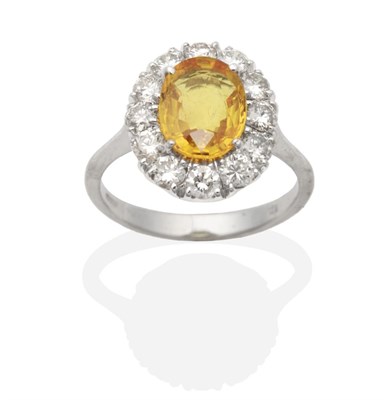 Lot 438 - An 18 Carat White Gold Yellow Sapphire and Diamond Cluster Ring, an oval cut yellow sapphire in...