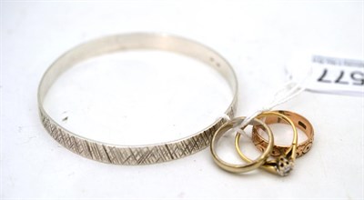 Lot 577 - Three 9ct gold rings, one diamond set, and a bangle