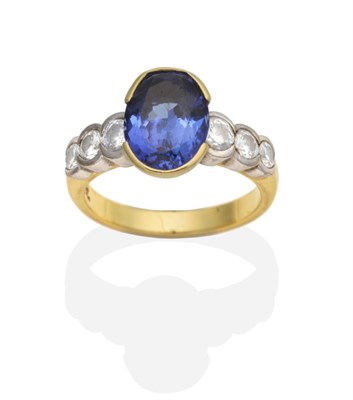 Lot 448 - A Tanzanite and Diamond Ring, an oval cut tanzanite in a half rubbed over setting, to shoulders...