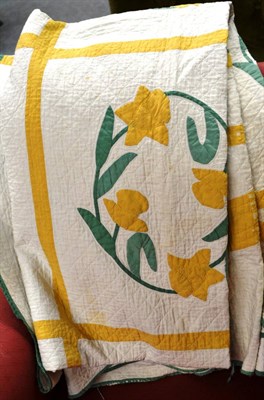 Lot 781 - An early 20th century quilt appliqued with circular daffodil floral motifs, within a yellow trellis