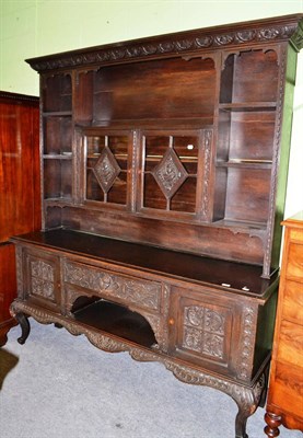 Lot 1455 - A large early 20th century stained oak dresser and rack with carved portrait plaques of Anne...