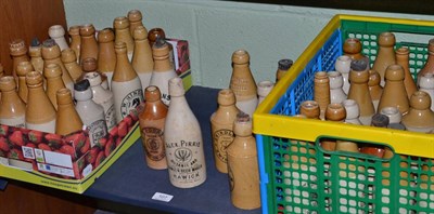 Lot 107 - A collection of approximately fifty stoneware ginger beer bottles, some with pictorial printed...