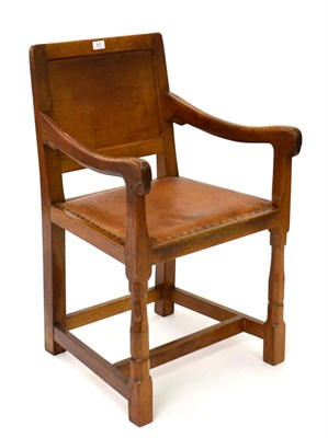 Lot 662 - Mouseman: A Robert Thompson English Oak Armchair, panel-back and shaped arms, upholstered tan...