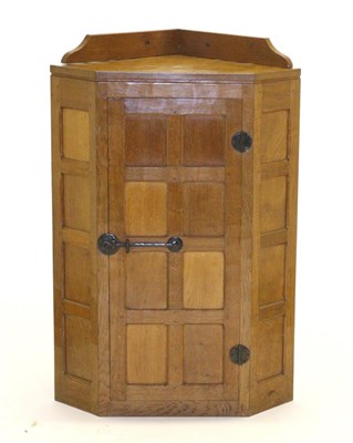 Lot 682 - Mouseman: A Robert Thompson Panelled Oak Hanging Corner Cupboard, the single door opening to reveal