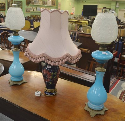 Lot 380 - Two blue opaline glass oil lamps and wells with glass chimneys and opaque shades, decorated...