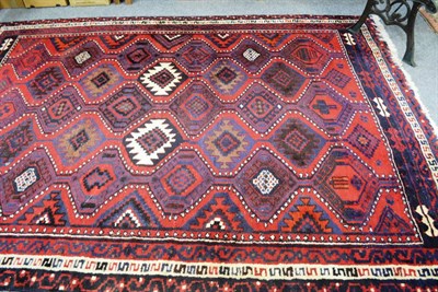 Lot 598 - Kurdish rug, Persian Kurdistan, the tomato red stepped lattice field of serrated guls enclosed...