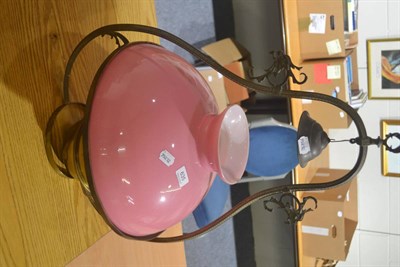 Lot 635 - A brass hanging paraffin lamp with a pink shade (missing chimney)