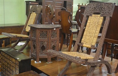 Lot 746 - Pair of carved Indian folding chairs with strawork seats and a similar carved occasional table