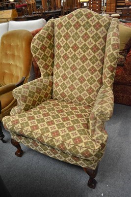 Lot 579 - A well upholstered Georgian style wing back armchair