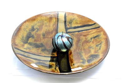 Lot 5601 - A Poole Pottery charger, decorated in gold and brown, together with an Isle of Wight glass...