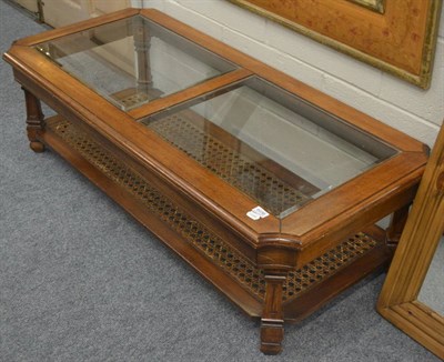 Lot 6036 - Modern glass top coffee table with a cane work shelf stretcher