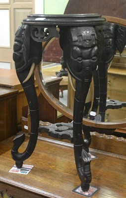 Lot 6281 - An ebonised plant stand carved with elephants