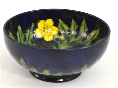 Lot 119 - A Moorcroft pottery bowl, tubelined and hand painted in the Buttercup pattern on a blue ground,...