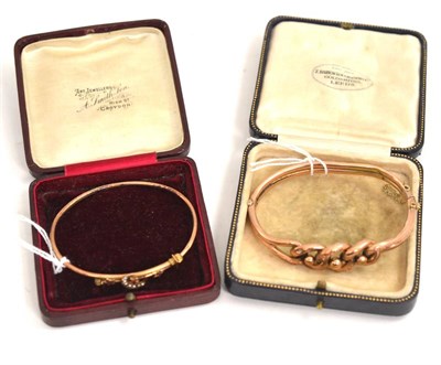 Lot 232 - A Victorian part engraved bangle, stamped '9C' and a crossover bangle, with seed pearl set crescent