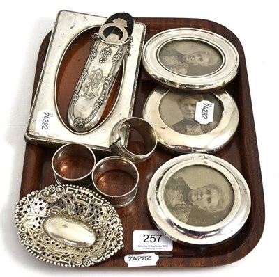 Lot 257 - A collection of silver comprising four photograph frames, a spectacle case, three napkin rings...