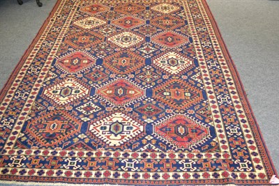 Lot 1108 - Afghan carpet of Caucasian design, the indigo hooked lattice field of polychrome guls enclosed...