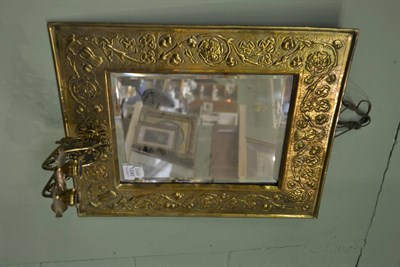 Lot 1290 - Arts & Crafts rectangular brass mirror, embossed with roses, mounted with twin candle sconces...