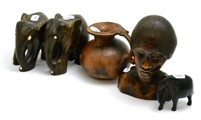 Lot 114 - A group of African tribal carvings including a bust, three elephants and a terracotta vase, the...