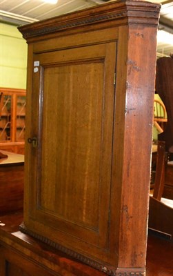 Lot 738 - George III oak hanging corner cupboard with dentil cornice and panelled door