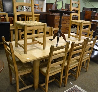 Lot 810 - A modern light oak kitchen table and ten ladder back rush seated chairs