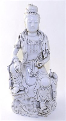 Lot 195 - A Blanc de Chine Figure of Guanyin, Qing Dynasty, sitting on a rock holding a scroll, a vase...