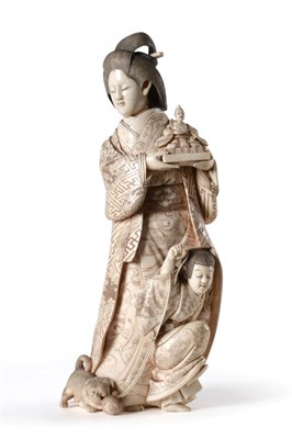 Lot 213 - A Japanese Ivory Okimono of a Geisha, Meiji period, standing holding a figure of an immortal, a...