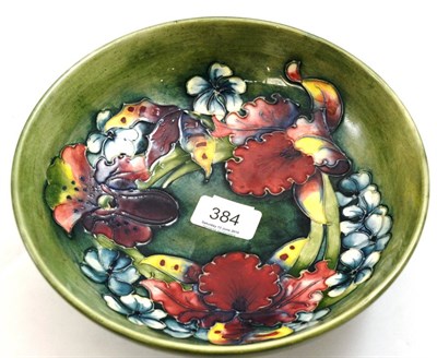 Lot 384 - A Walter Moorcroft Orchid and Spring Flowers pattern bowl, on a green ground, impressed factory...