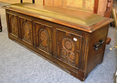 Lot 1148 - A reproduction oak chest, with carved panelled front and leather studded top