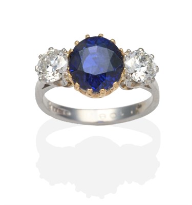 Lot 400 - A Platinum Sapphire and Diamond Three Stone Ring, a round cut sapphire in a yellow claw setting...
