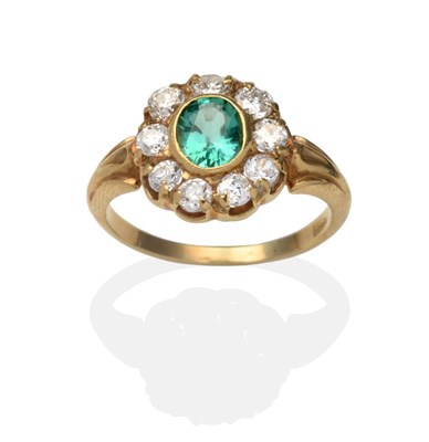 Lot 402 - An Emerald and Diamond Cluster Ring, an oval cut emerald in a yellow rubbed over setting,...