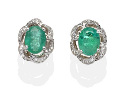 Lot 427 - A Pair of Emerald and Diamond Cluster Earrings, an oval cut emerald in a white claw setting...