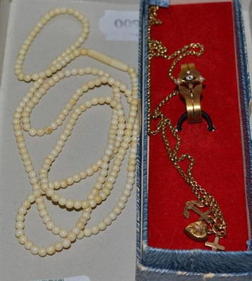 Lot 388 - A 15ct gold scarf clip, three 9ct gold charms on gilt chain and ivory beads