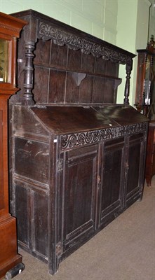 Lot 481 - An 18th century large oak dresser with two hinged sloping doors to the top and rack with carved...