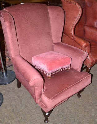 Lot 541 - Dark pink upholstered wing armchair and similar footstool