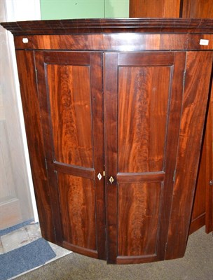 Lot 540 - A George III mahogany bow front corner cupboard