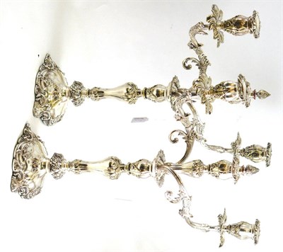 Lot 71 - A pair of silver plated three branch candelabra, the shaped bases and baluster stems with...