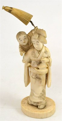 Lot 335 - A Japanese Meji period carved ivory okimono of a mother and child, the child with his arm...