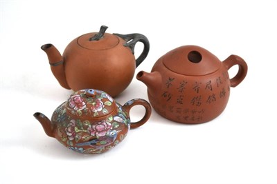 Lot 349 - Three Chinese Yixing teapots, one with famille rose enamels, another incised with an...