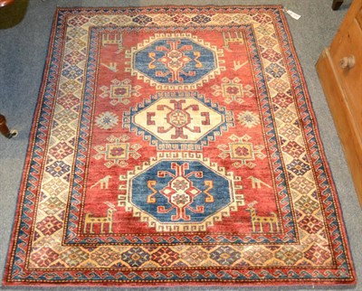 Lot 1244 - An Afghan rug of Caucasian design, the blood red field with three octagons surrounded by zoomorphic