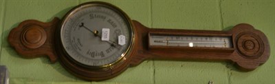 Lot 1255 - A 20th century oak cased aneroid barometer, with thermometer, circular silvered dial, carved...