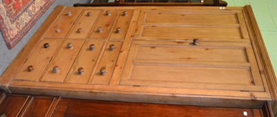 Lot 1269 - A 19th century pine cupboard with a bank of eight drawers below two panelled doors enclosing...