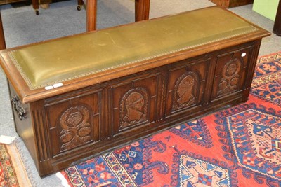 Lot 1364 - A reproduction oak chest, with carved panelled front and leather studded top