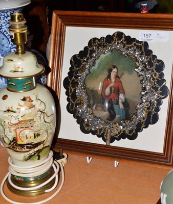 Lot 157 - A chinoiserie decorated table lamp and a papier mache face screen in a glazed frame (2)