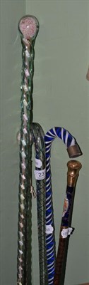 Lot 231 - A walking cane with porcelain grip and four glass walking stick friggers