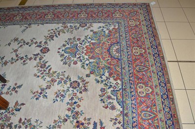 Lot 572 - A machine made carpet of Oriental design, the pale mushroom field centred by a terracotta pole...