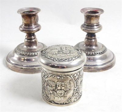 Lot 125 - A pair of small plated candlesticks on circular bases and a silver circular box and cover, repousse