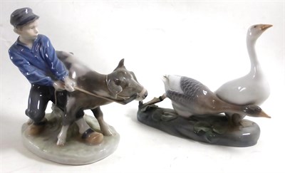 Lot 458 - Two Royal Copenhagen china figures, one modelled as a young boy with a cow, the other a group...