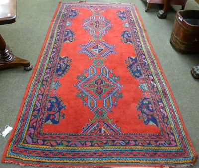 Lot 1263 - A Ushak rug, central turkey, the tomato red field with three skeletal medallions enclosed by narrow